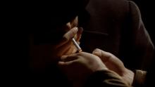 Screenshot from The Godfather (1972).  One person holds a lighter for another lighting his cigarette.  